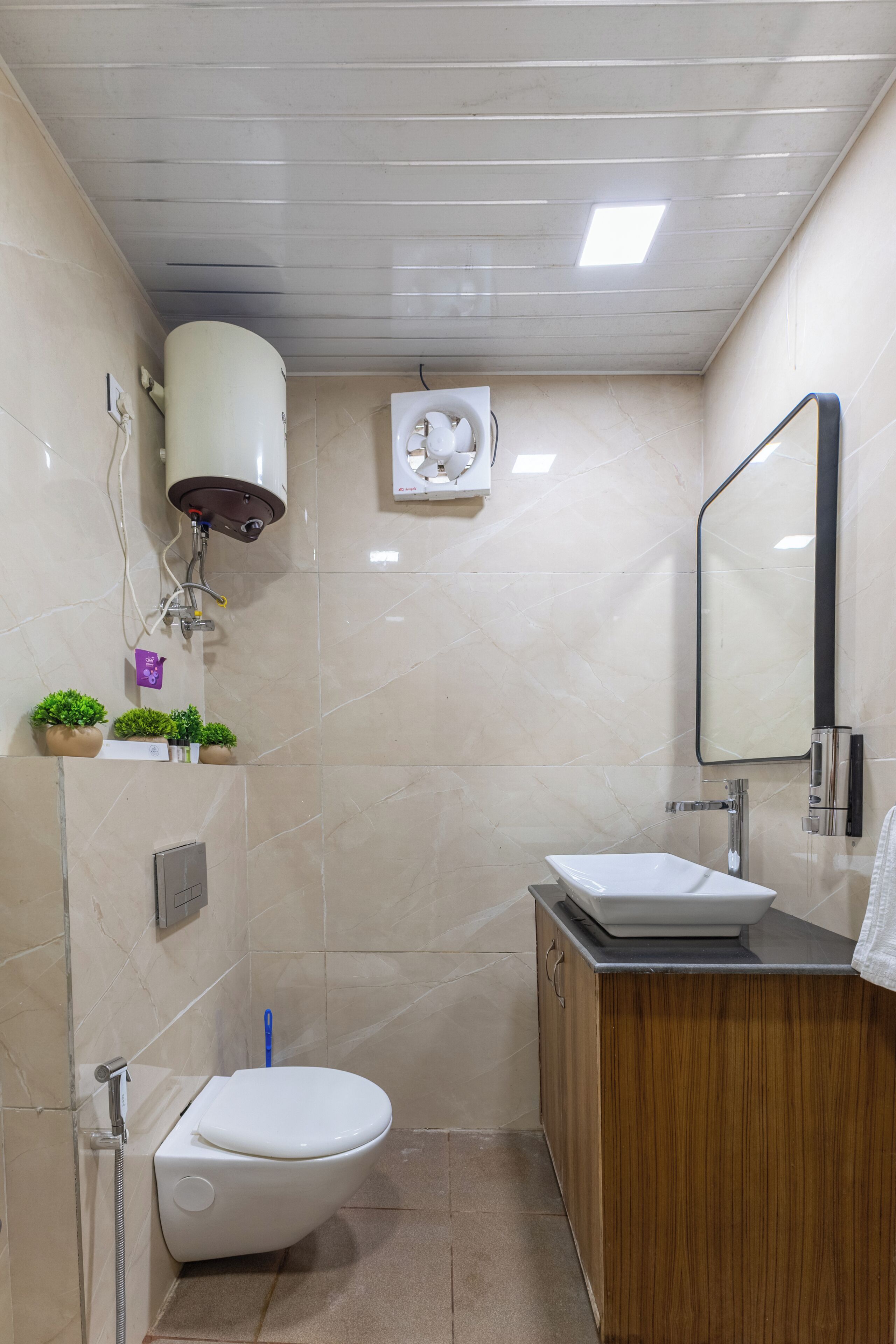 A bathroom with a toilet, sink, mirror, and a ceiling fan.