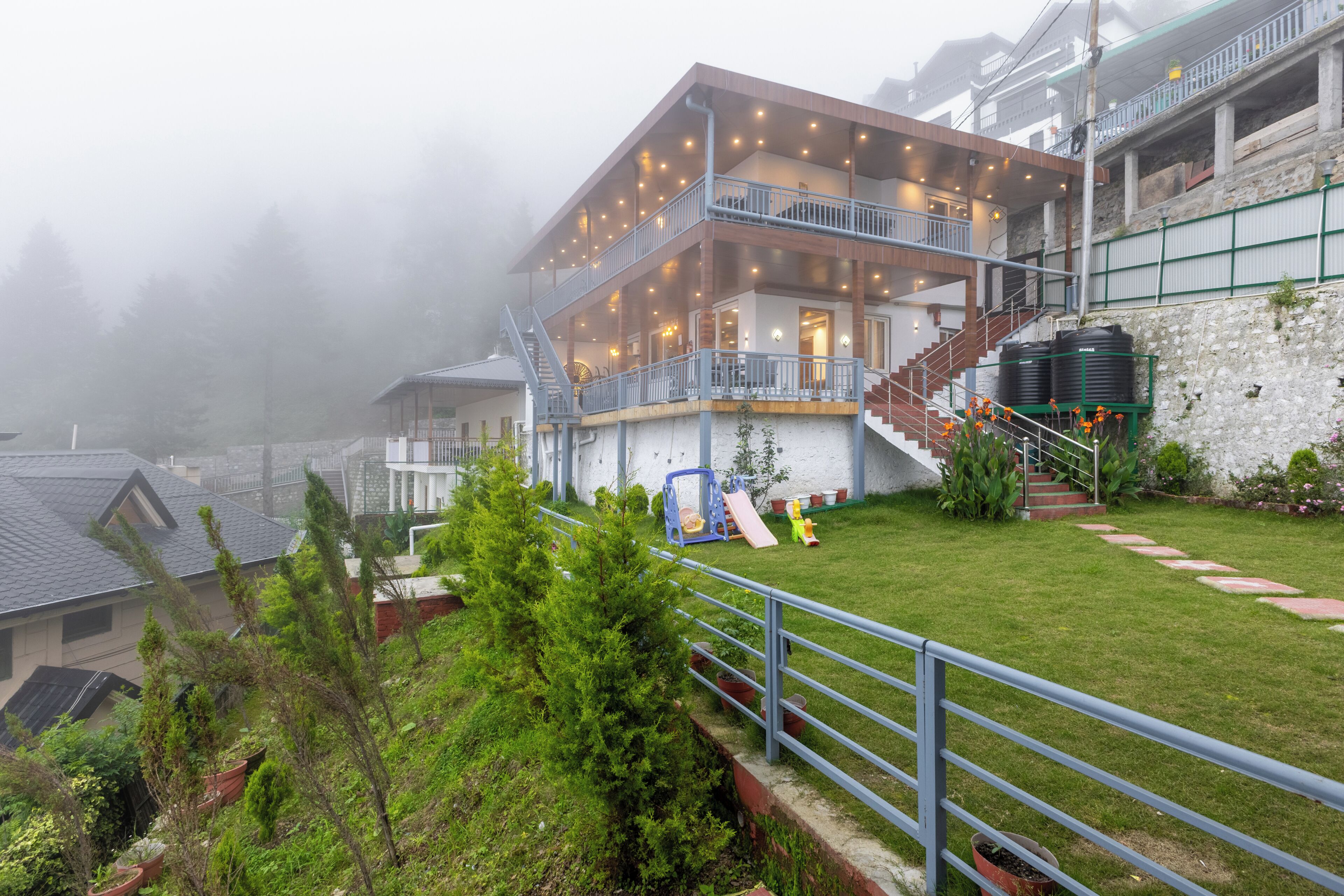 A multi-story hotel with balconies, a staircase, and a garden area.