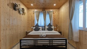 Une pièce aux murs lambrissés, avec un lit, des rideaux et une fenêtre.