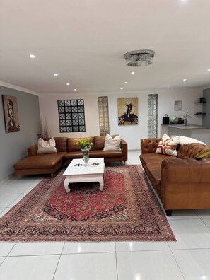 Een moderne woonkamer met twee leren banken, een witte salontafel en een vloerkleed met een patroon.