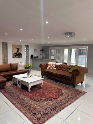 Ein Wohnzimmer mit einem braunen Ledersofa, einem weißen Couchtisch und einem gemusterten Teppich.