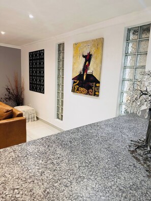 A modern living room with a granite countertop, a brown leather sofa, and two abstract paintings on the wall. - Entertainers delight near the beach & wine routes! (Cape Town)