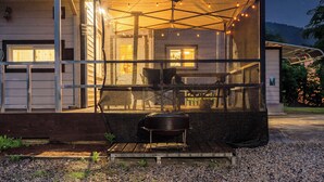 Un área de estar al aire libre con techo, una parrilla, una mesa de comedor y sillas.