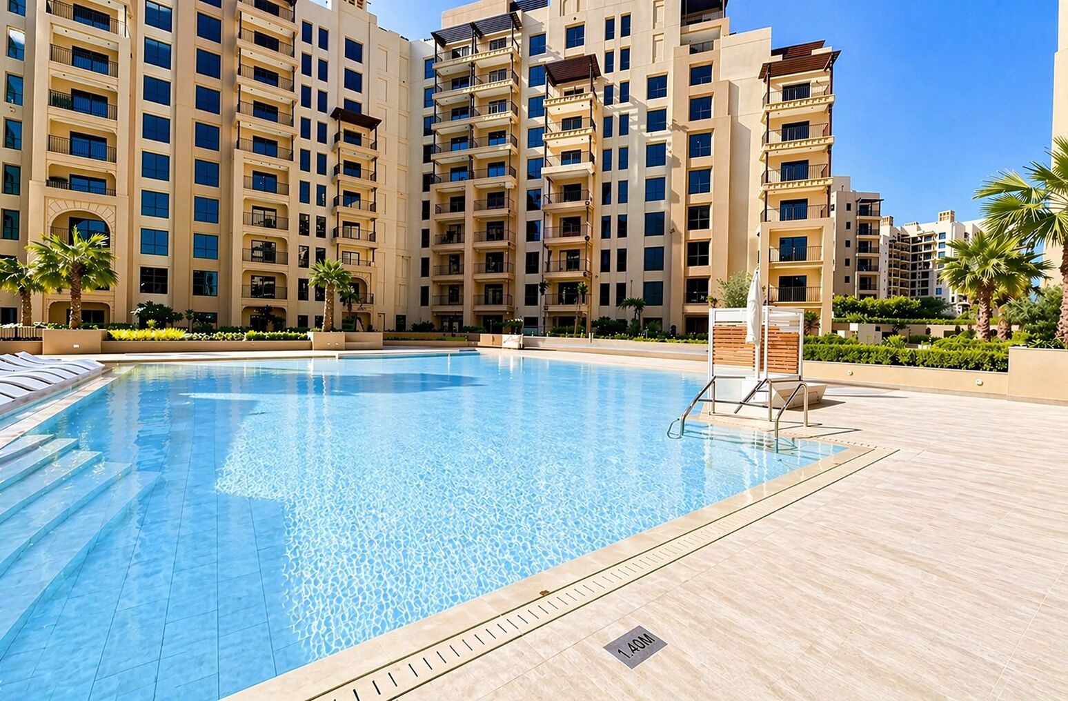 Ein Swimmingpool mit glatter, blauer Wasseroberfläche, umgeben von einer gefliesten Liegefläche und Palmen.