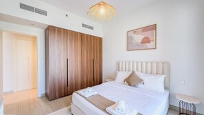 Un dormitorio moderno con una cama grande, un armario, una mesita de noche y una lámpara colgante.