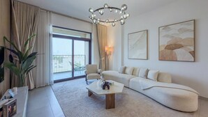 A modern hotel room with a large window, a sofa, a coffee table, and artwork on the walls. - Jadeel Residences- MJL - Dubai (Dubai)