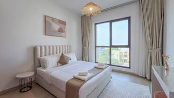 Ein Hotelzimmer mit einem großen Bett, einem Nachttisch, einem kleinen runden Tisch, einem Fenster mit Vorhängen und einer Pendelleuchte.