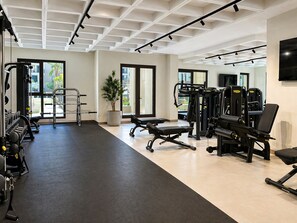 A gym with exercise equipment, large windows, and a potted plant. - Jadeel Residences- MJL - Dubai (Dubai)