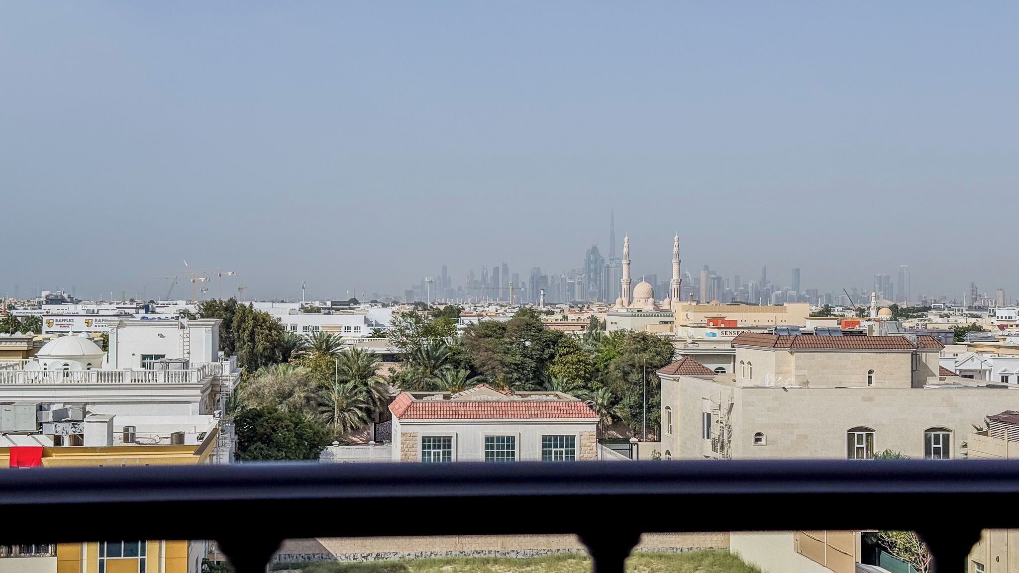 Stadsgezicht met een opvallende moskee met twee minaretten, omringd door woongebouwen en een verre skyline.