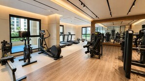A gym with cardio machines, weight training equipment, and a large mirror. - Jadeel Residences- MJL - Dubai (Dubai)