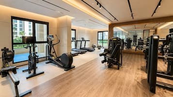 Ein Fitnessstudio mit Laufbändern, Krafttrainingsgeräten und einem großen Spiegel.