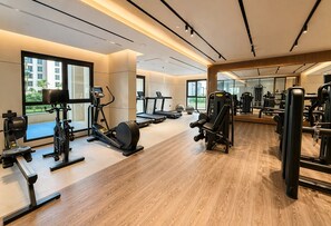 A gym with cardio machines, weight training equipment, and a large mirror. - Jadeel Residences- MJL - Dubai (Dubai)