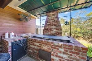 An outdoor barbecue area with a brick chimney, a fan, and a grill. - Shared BBQ Area & Pool! Cozy Home in Lake Charles (Lake Charles)