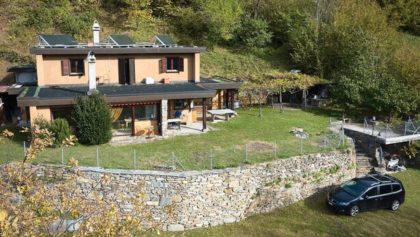 A two-story house with a stone wall and a car parked in front. - Casa Bubeck by Interhome (Sobrio)
