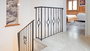 A staircase with a metal railing, a wooden floor, a bed with a white mattress, and a painting on the wall. - Casa Bubeck by Interhome (Sobrio)