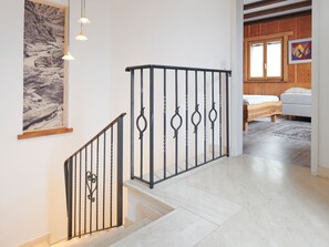 A staircase with a metal railing, a wooden floor, a bed with a white mattress, and a painting on the wall. - Casa Bubeck by Interhome (Sobrio)