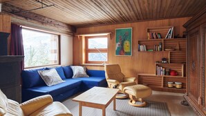 A cozy living room with a blue sofa, a wooden coffee table, and a bookshelf filled with books and decorative items. - Casa Bubeck by Interhome (Sobrio)