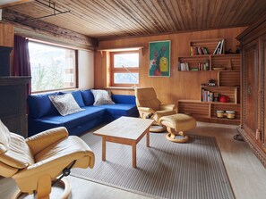 A cozy living room with a blue sofa, a wooden coffee table, and a bookshelf filled with books and decorative items. - Casa Bubeck by Interhome (Sobrio)
