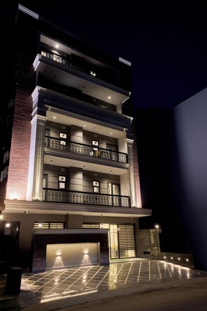 Un edificio de varios pisos con garaje en la planta baja, balcones en cada nivel y fachada de ladrillo.