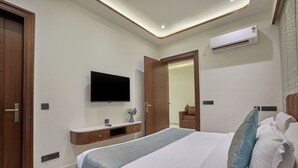 Un dormitorio moderno con cama, televisor, cómoda y aire acondicionado.