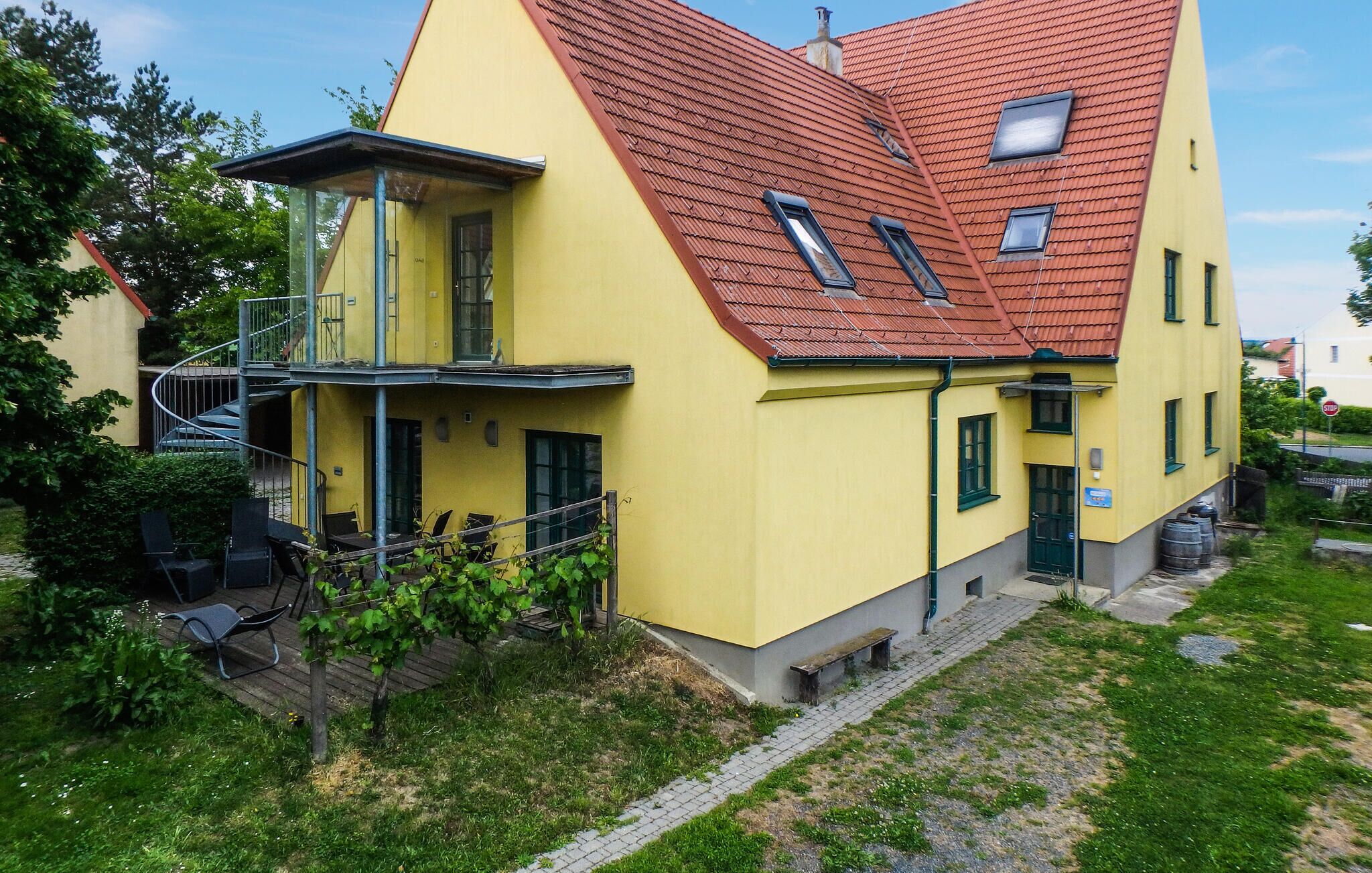 A yellow building with a red roof, a balcony, and a staircase leading to an upper floor.