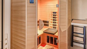 Et sauna-rum med kontrolpanel, en træbænk og en reol.