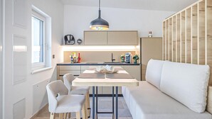 Et kompakt køkken med spiseplads, en sofa og en væg med træpaneler.