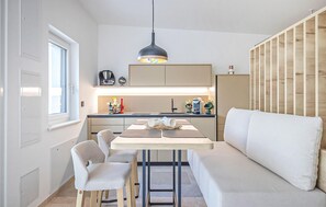A compact kitchen with a dining area, a sofa, and a wooden panel wall. - Gorgeous home in Stegersbach with sauna (Stegersbach)