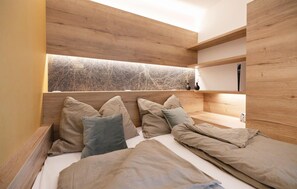 A modern bedroom with a wooden headboard, multiple pillows, a bedside table, and a wall-mounted shelf. - Gorgeous home in Stegersbach with sauna (Stegersbach)