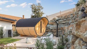 Un edifici amb forma de barril, paret de pedra i terrassa de fusta.