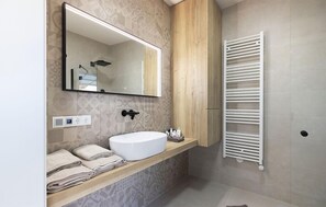 A modern bathroom with a large mirror, a white sink, and a towel rack. - Awesome home in Stegersbach with sauna (Stegersbach)