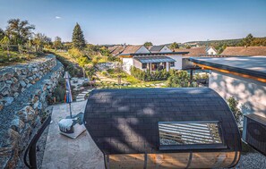 A residential area with a stone wall, a modern house with a sloped roof, and a clear sky. - Awesome home in Stegersbach with sauna (Stegersbach)