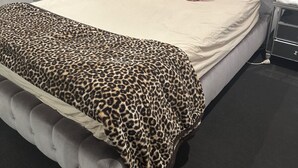 A bedroom with a tufted headboard, a bed with a leopard print bedspread, and a bedside table with a lamp. - Room-cozy Room Rental in Caloundra West (Sunshine Coast)