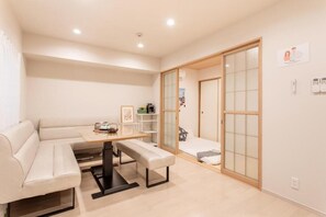 A modern room with a sofa, a table, and a sliding door leading to a balcony. - Cloud&Maple (Nishinari Ward)