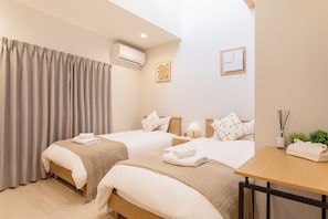 A hotel room with two beds, a wooden nightstand, a table, an air conditioning unit, and a window with curtains. - Cloud&Maple (Nishinari Ward)