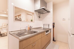 A modern kitchen with a stainless steel sink, wooden cabinets, a built-in oven, and a microwave. - Cloud&Maple (Nishinari Ward)