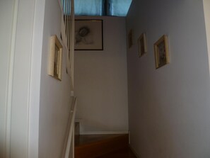 Eine schmale Treppe mit einer Holzhandläufe und einer weißen Wand.