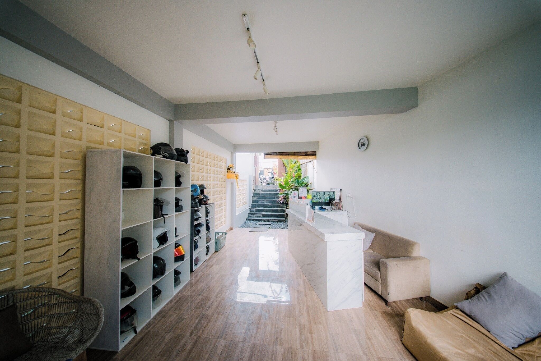 A hallway with a shoe rack, a sofa, and a staircase leading to another room.