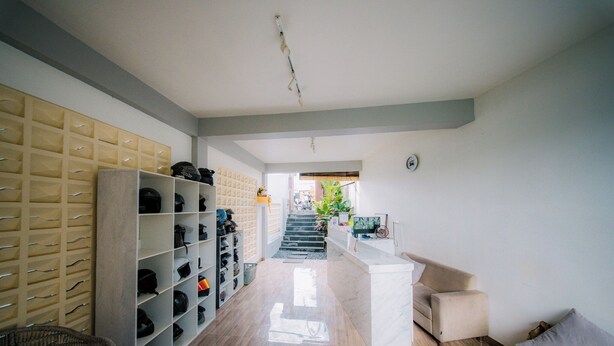 A hallway with a shoe rack, a sofa, and a staircase leading to another room. - Puspa Guest House (Pererenan)