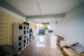 A hallway with a shoe rack, a sofa, and a staircase leading to another room. - Puspa Guest House (Pererenan)