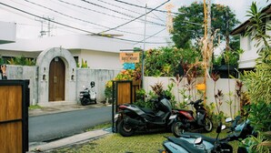 A guest house with a sign indicating availability, a paved entrance, and a row of parked motorcycles. - Puspa Guest House (Pererenan)