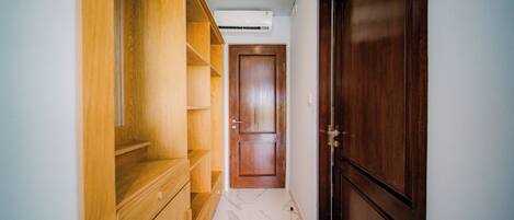A hallway with a wooden cabinet, a marble floor, and a closed wooden door.
