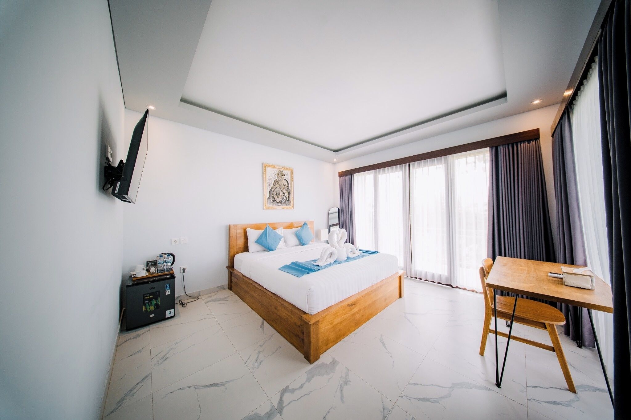 Habitación de hotel moderna con una cama grande, un escritorio y vistas al exterior.