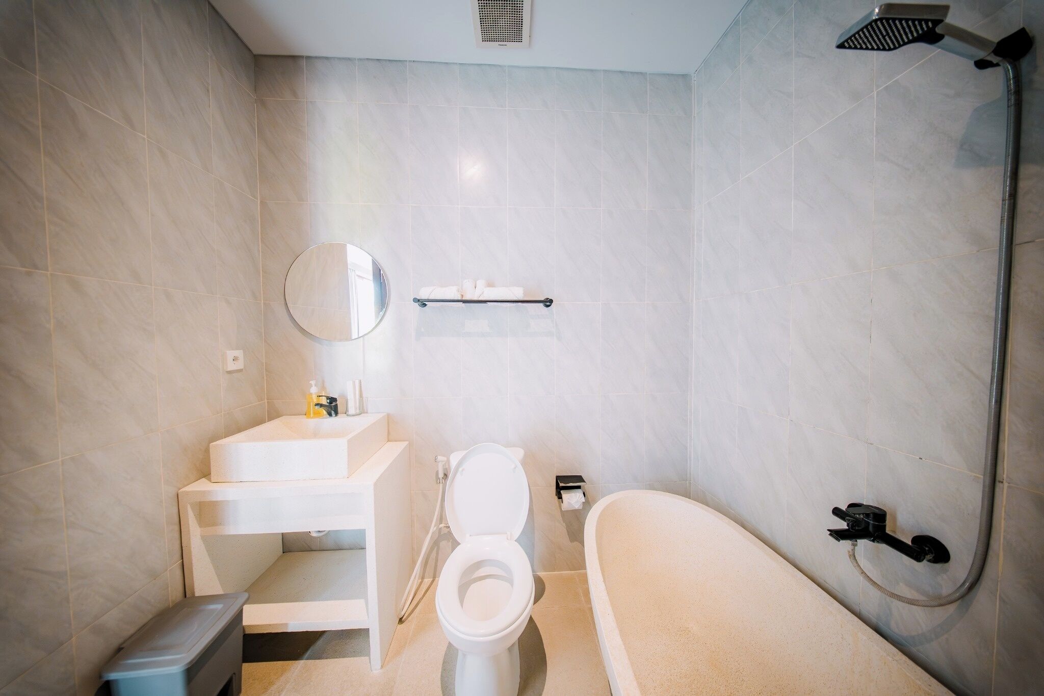 Un baño moderno con inodoro, lavamanos, espejo y ducha.