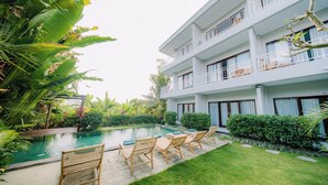 A hotel with a pool, outdoor seating, and lush greenery. - Puspa Guest House (Pererenan)