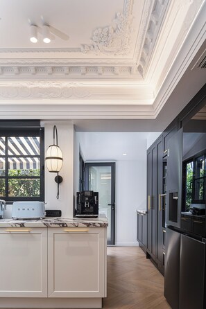 A modern kitchen with a marble countertop, a coffee machine, and a black refrigerator. - Exclusive Serviced Penthouse in Kolonaki (Athens)