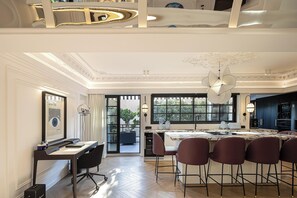 A modern kitchen with a dining area, featuring a chandelier, a large window, and a view of the outdoors. - Exclusive Serviced Penthouse in Kolonaki (Athens)