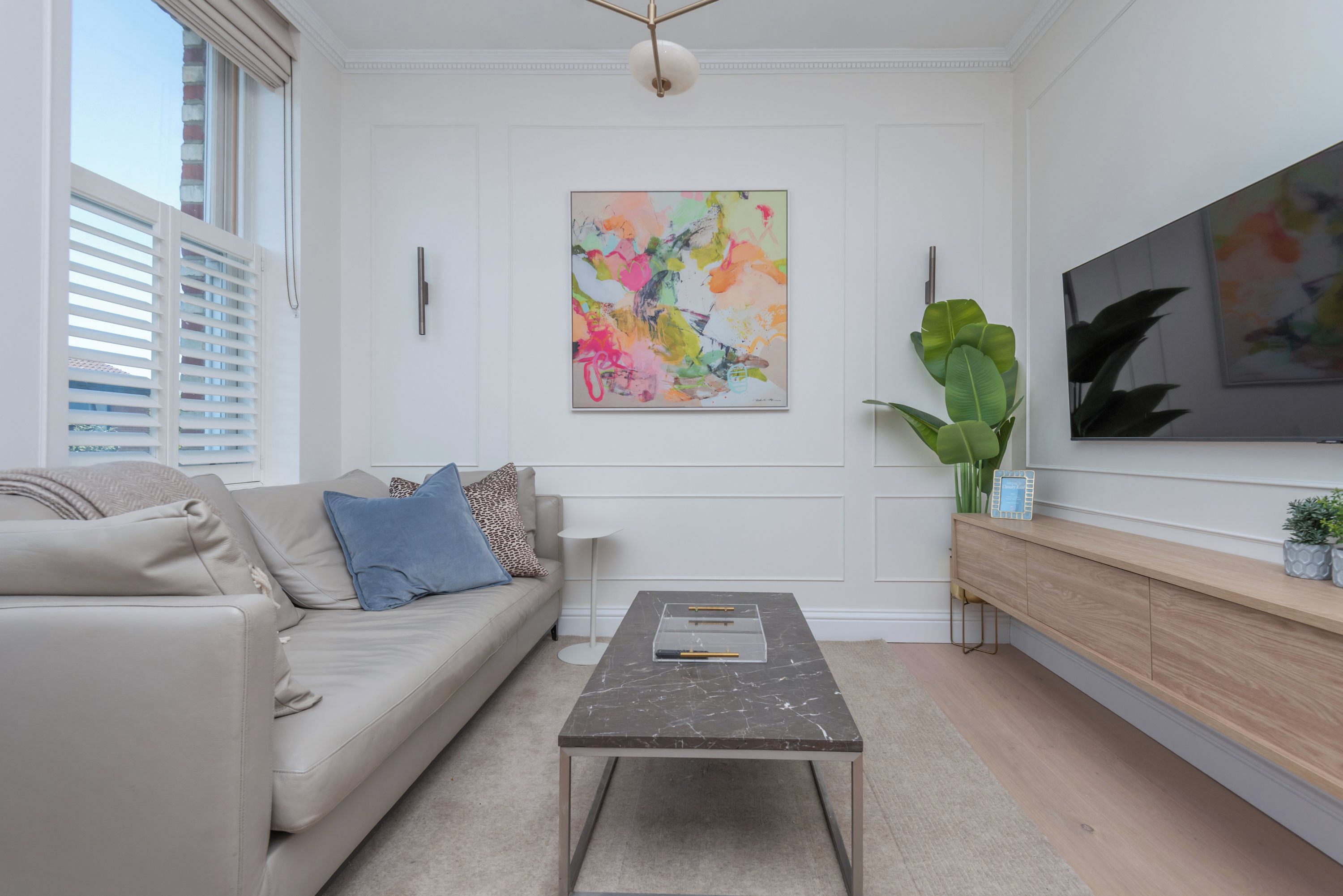 A modern living room with a sofa, coffee table, and artwork on the wall.