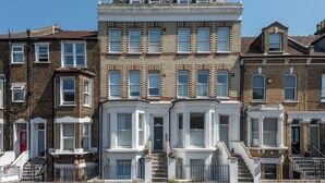 A row of terraced houses with bay windows and a central entrance. - Modern 2BDR with Workspace in Clapham Junction (Greater London)