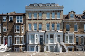 A row of terraced houses with bay windows and a central entrance. - Modern 2BDR with Workspace in Clapham Junction (Greater London)